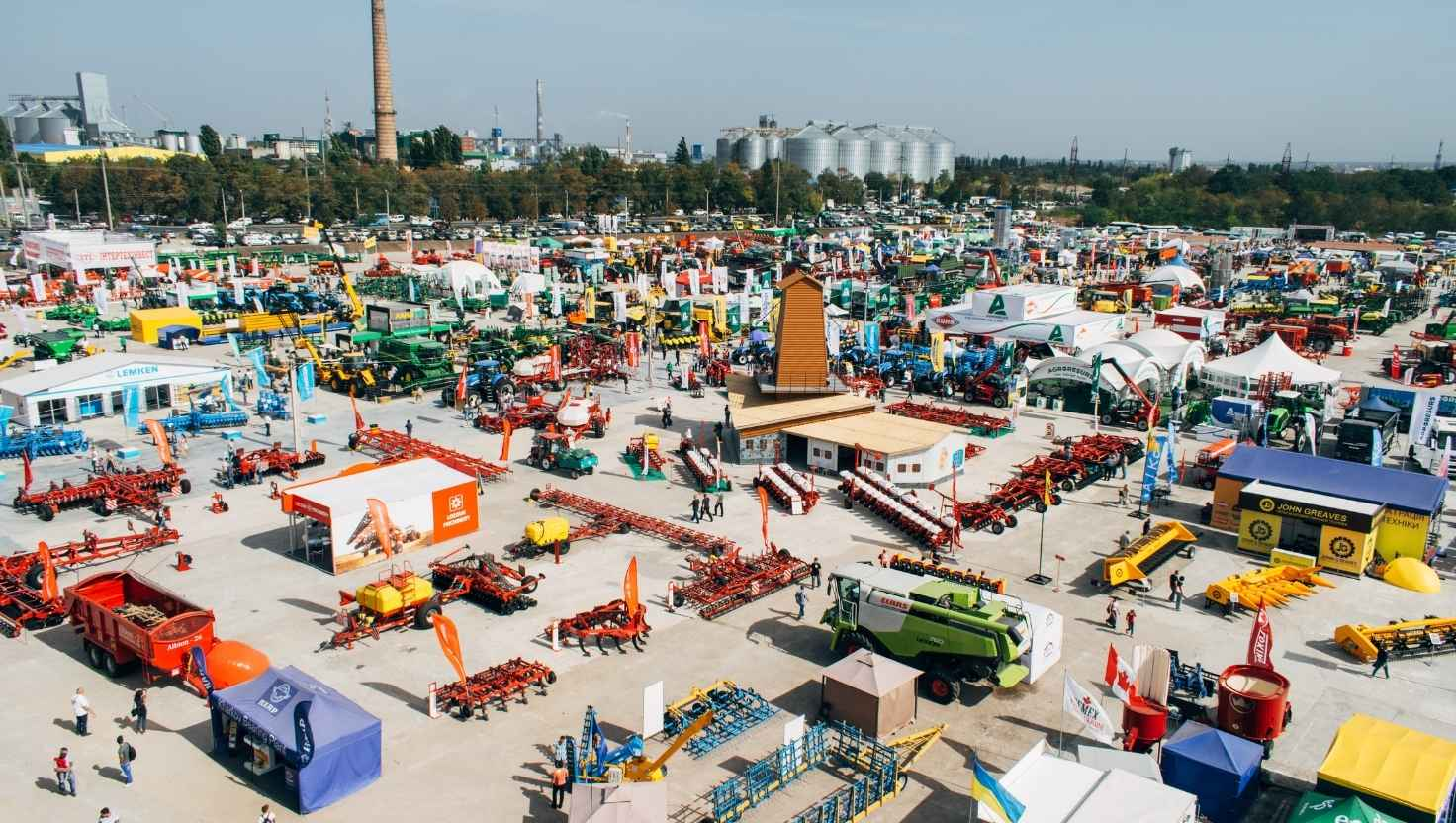 Área externa de feira do agronegócio com estandes, tendas e máquinas agrícolas em exposição, semelhante à Expolondrina
