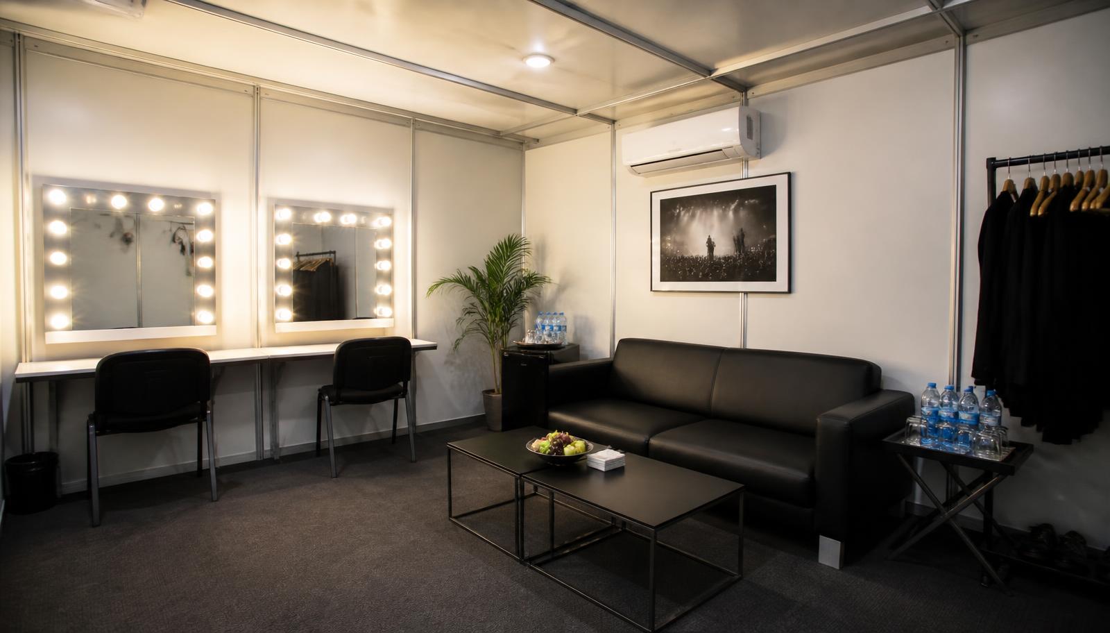Interior de camarim em Octanorm com espelhos iluminados, bancada, sofá, ar-condicionado e arara de roupas