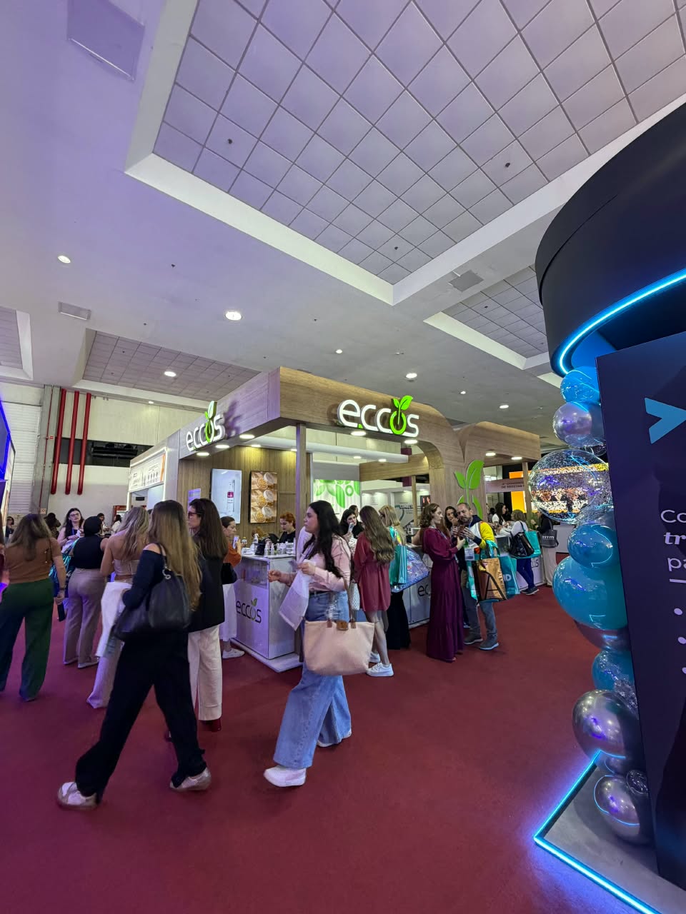 Visitantes no corredor de feira com stands montados pela DL
