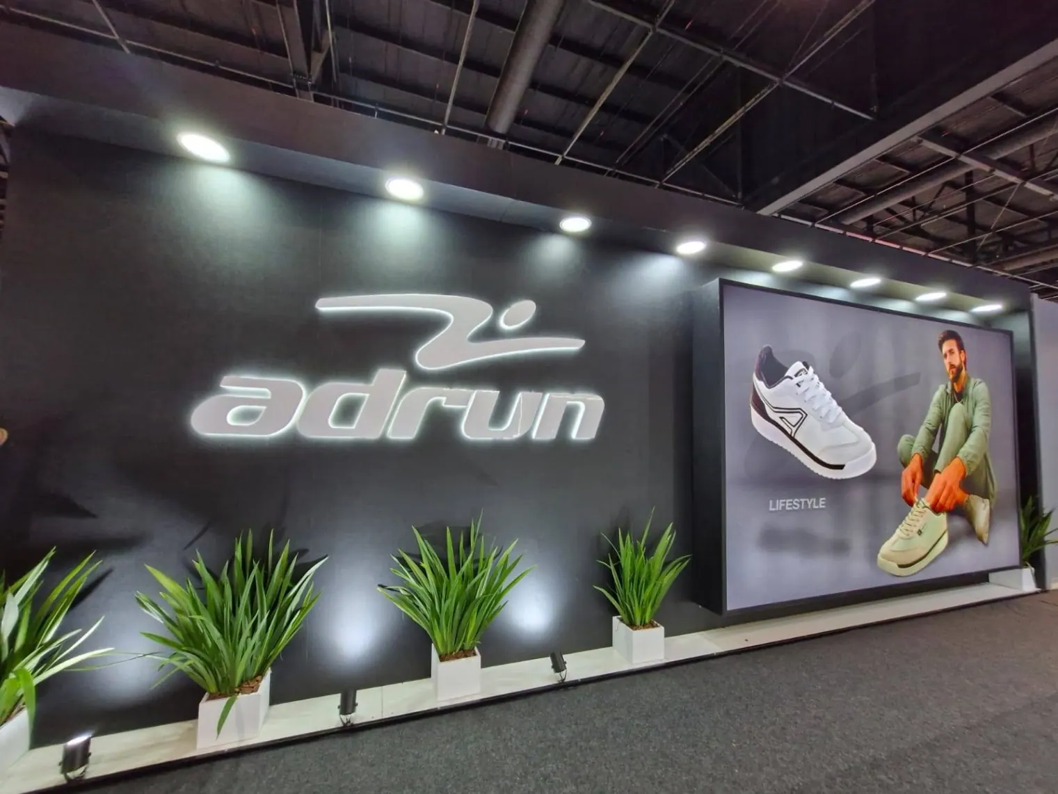 Stand Adrun - fachada preta com logo iluminado e paisagismo