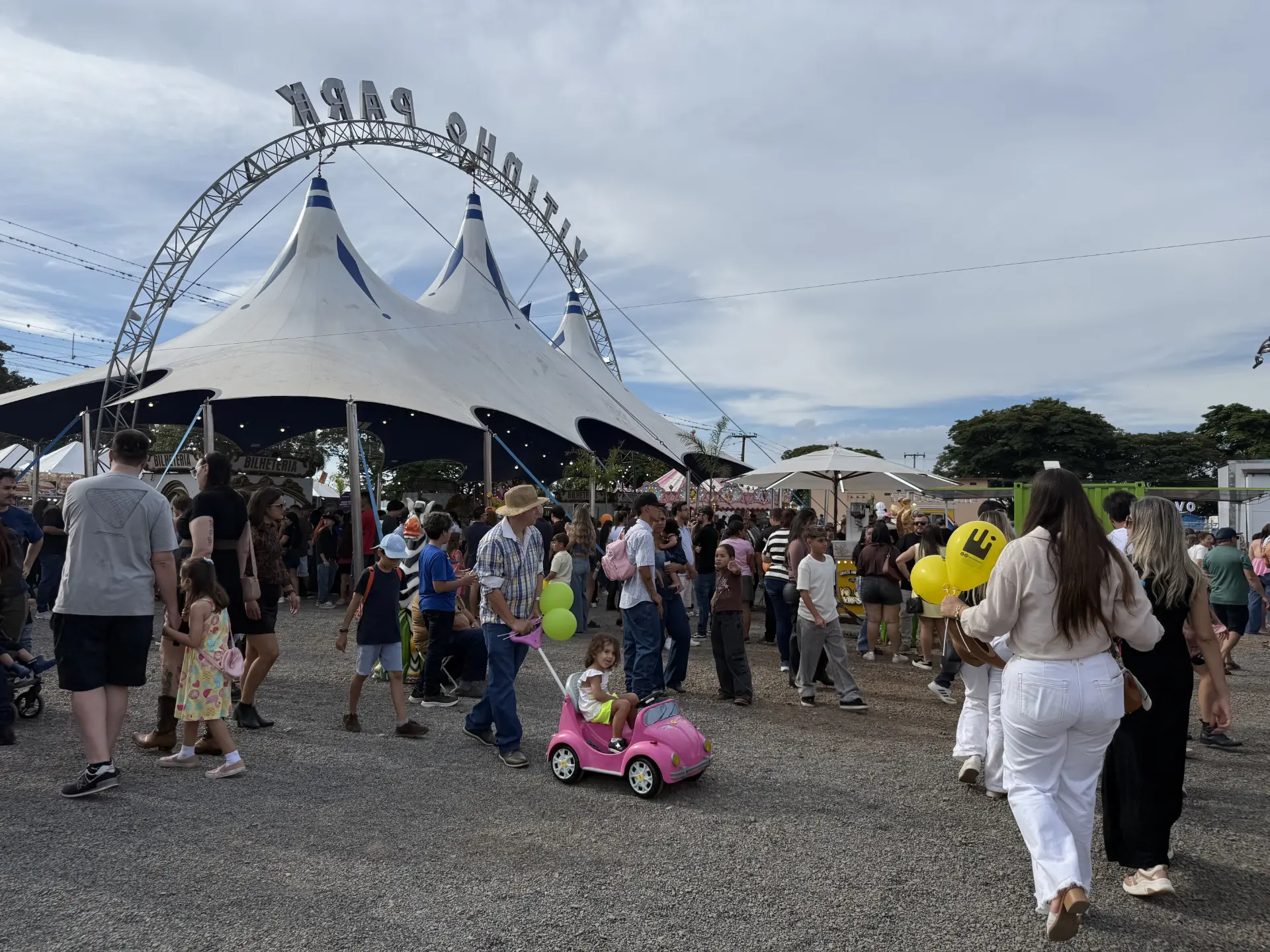 Público circulando entre tendas e estruturas de lona em parque de exposições durante feira