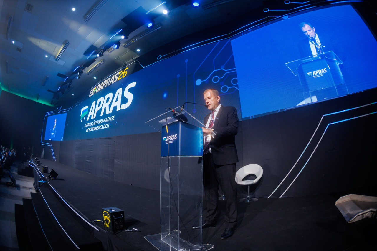 Palestrante no palco do congresso da ExpoApras com painel de LED e cenografia corporativa em azul
