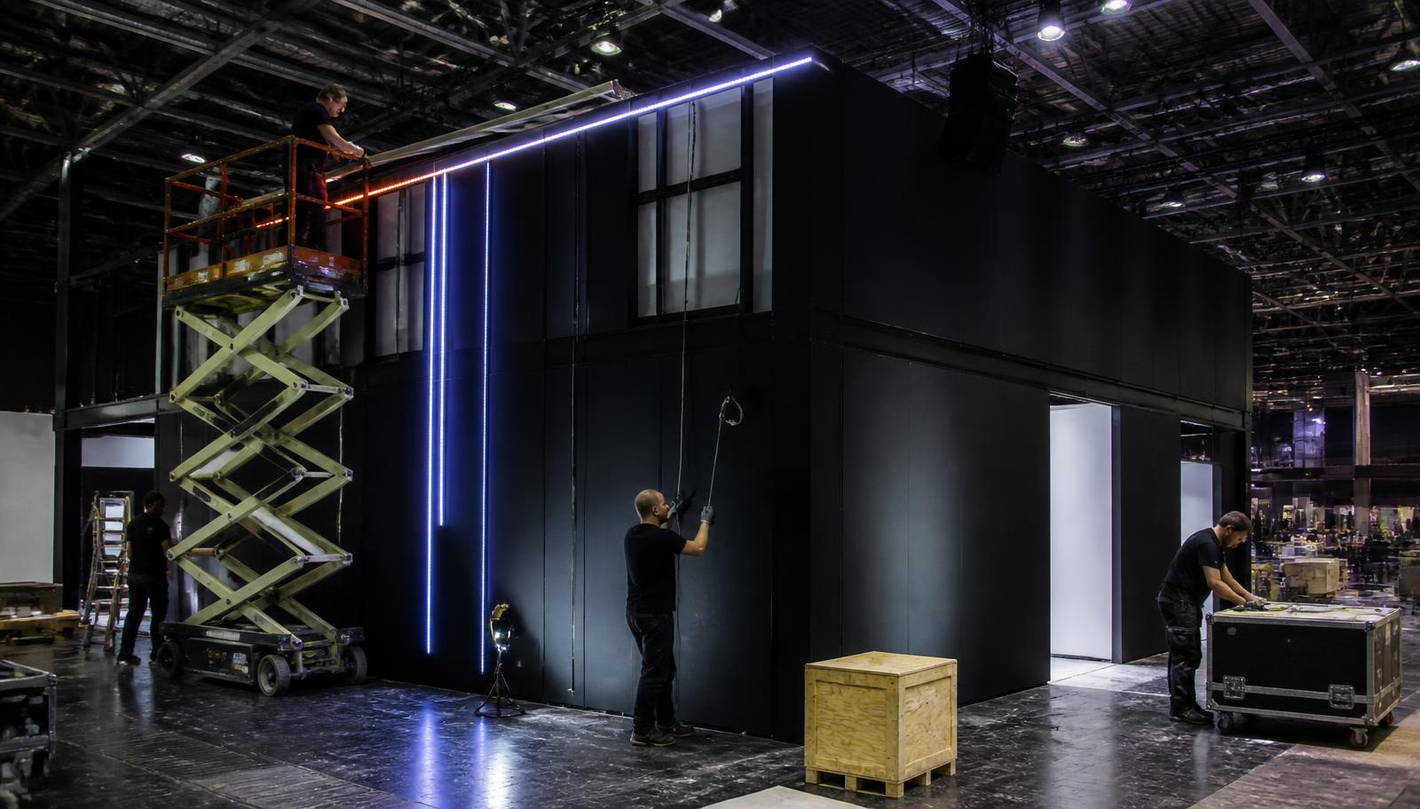 Equipe montando estrutura de stand com iluminação em LED no pavilhão