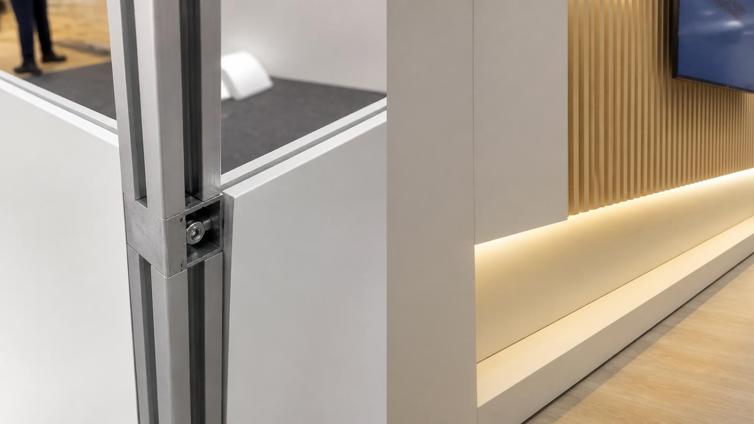 Detalhe do encaixe do perfil de alumínio Octanorm ao lado de uma parede de marcenaria pintada com sanca de LED embutido