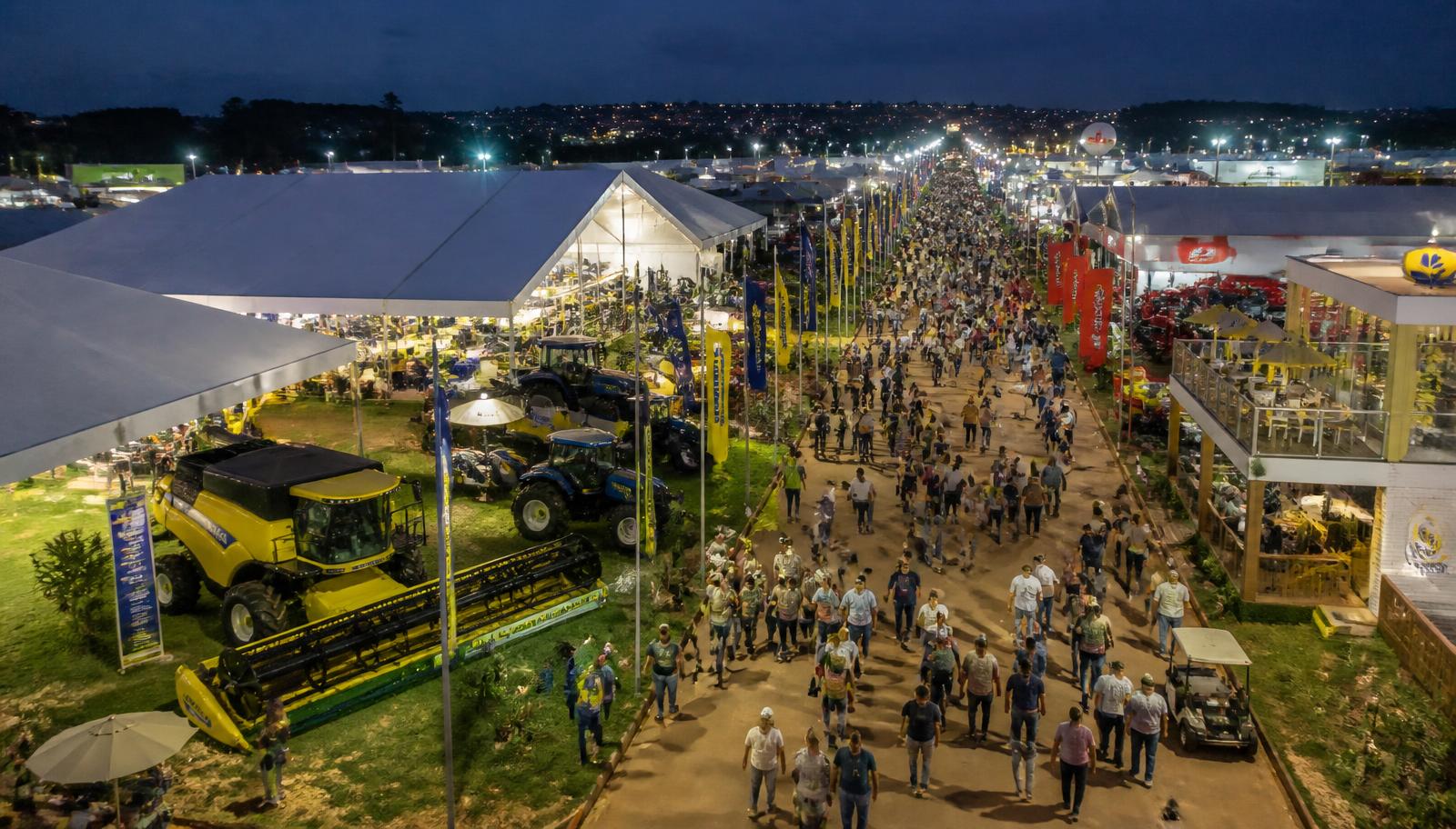 Vista aérea do parque da Show Rural Coopavel em Cascavel, com alamedas movimentadas, tendas brancas, máquinas agrícolas e milhares de visitantes