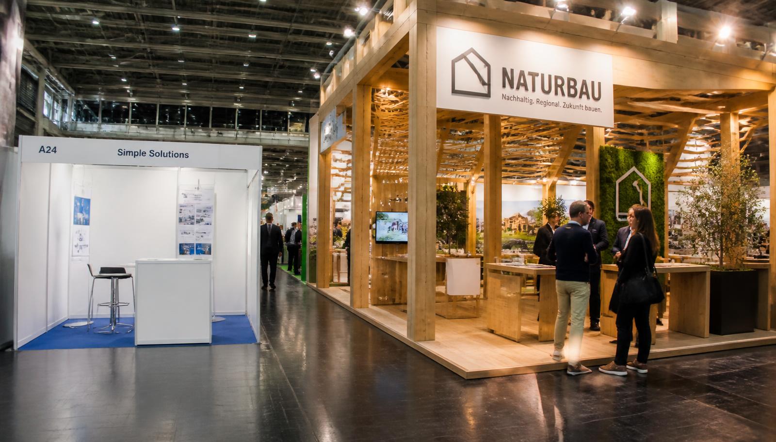 Comparação em corredor de feira entre um stand modular branco básico e um stand construído em madeira com arquitetura autoral