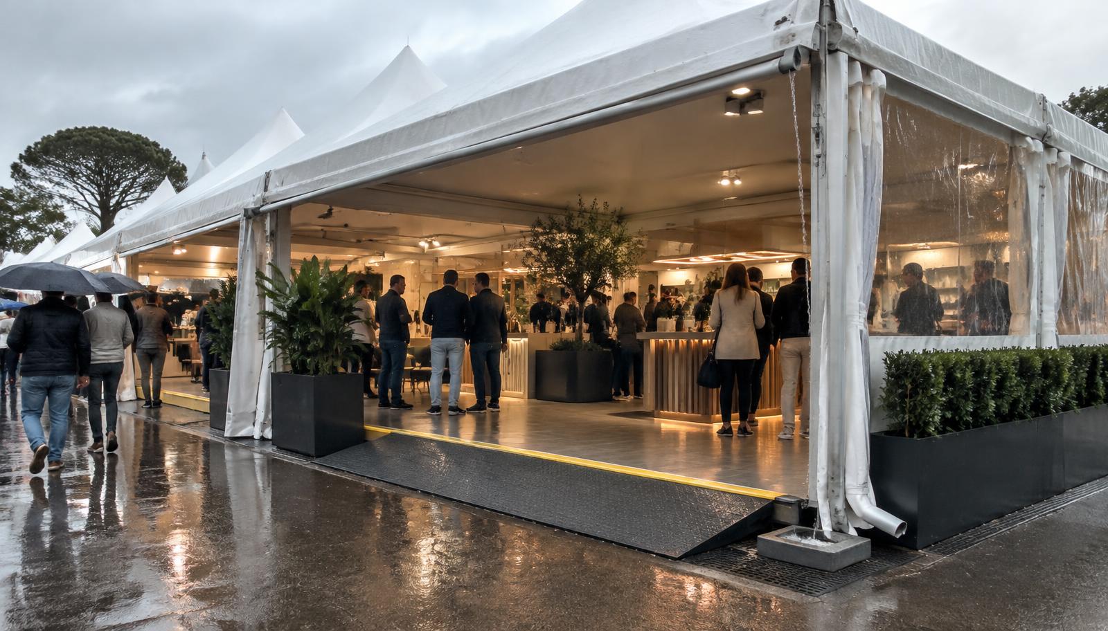 Stand sob tenda protegido durante chuva com calhas, piso seco e acesso por rampa